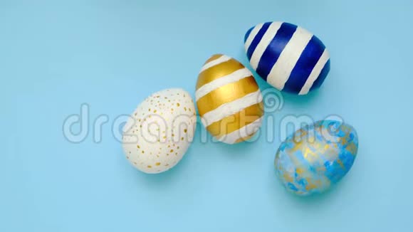 复活节彩蛋滚滚互相敲着蓝桌子鸡蛋时髦的彩色经典蓝色白色和金色快乐视频的预览图