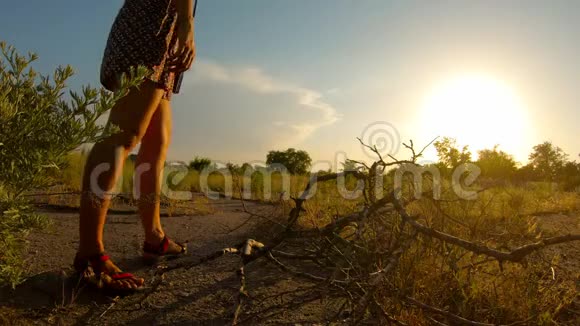 穿着短裙的女孩沉思地走着夕阳的光芒在一个村庄附近的夏天视频的预览图