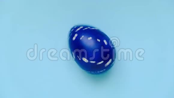 复活节彩蛋在蓝色桌子上旋转鸡蛋时髦的彩色经典蓝色白色和金色复活节快乐最小视频的预览图