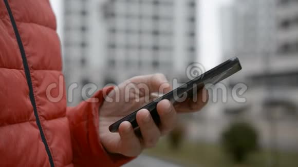 一个穿红色夹克的男人在电话里接了一条短信视频的预览图