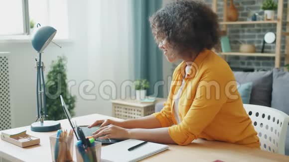 快乐的少年在家里用笔记本电脑打字然后在笔记本上记笔记视频的预览图