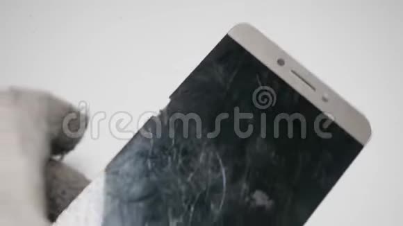 双手戴白色手套擦拭旧智能手机的脏破屏幕关闭视野视频的预览图