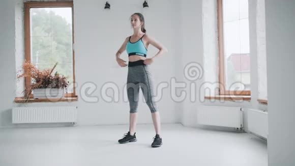 年轻的黑发女孩穿着运动装拳击在明亮的房间在家做运动视频的预览图