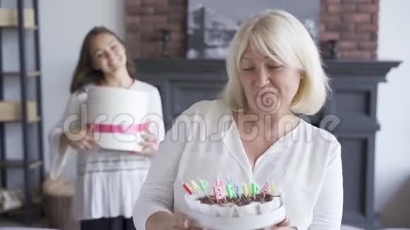 年长的女人给相机看蛋糕年轻女子站在后台庆祝生日视频的预览图