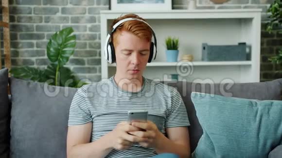 使用智能手机触摸屏幕的青少年在家享受音乐视频的预览图