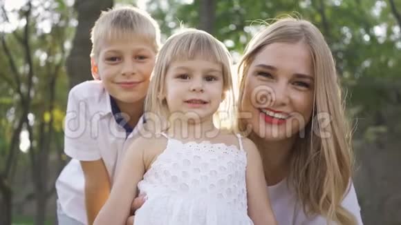 漂亮的金发女人和她的两个孩子看着相机微笑小男孩小女孩和有魅力的女人视频的预览图