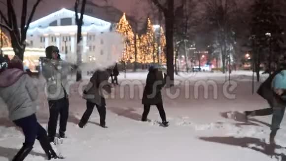 一群朋友在冬天的雪夜在城市公园玩雪球玩得很开心年轻的白种人喜欢下雪视频的预览图