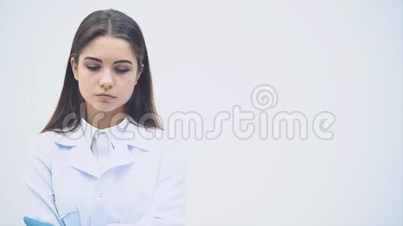 年轻的女实习生站在医疗制服上认真地看着镜头摆姿势双手交叉视频的预览图
