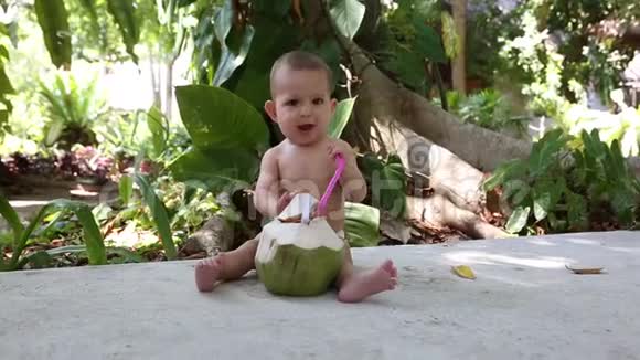 婴儿坐着新鲜的绿色椰子嚼一根稻草那孩子痒痒的视频的预览图