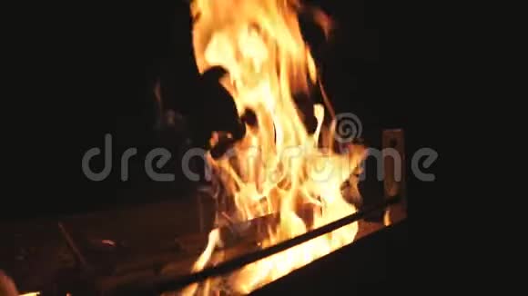 红色的火焰从黑色背景下燃烧的木片中升起柴禾晚上烧烤篝火视频的预览图