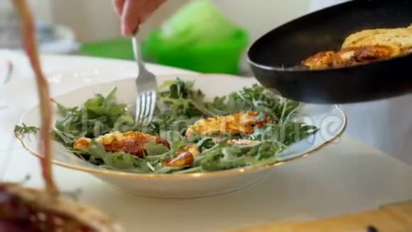 一只雌性的手把一个油炸的halumi奶酪和一个叉子放在叶上做一份美味的沙拉4k视频视频的预览图