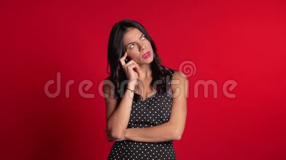 思考女人在红色背景上抬头看了看担心沉思的面部表情拉丁女模特视频的预览图