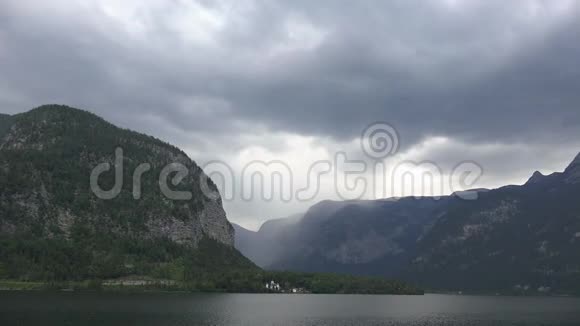 雨云在霍尔斯特湖上消失了一个的塔看到阿尔卑斯山村庄附近的霍尔斯塔特有山和小城堡视频的预览图