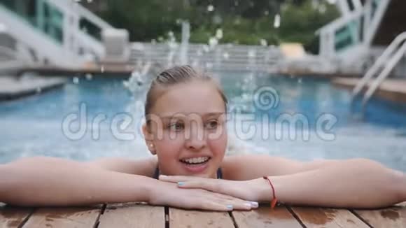 一个微笑的十几岁女孩的肖像在游泳池的边缘特写视频的预览图