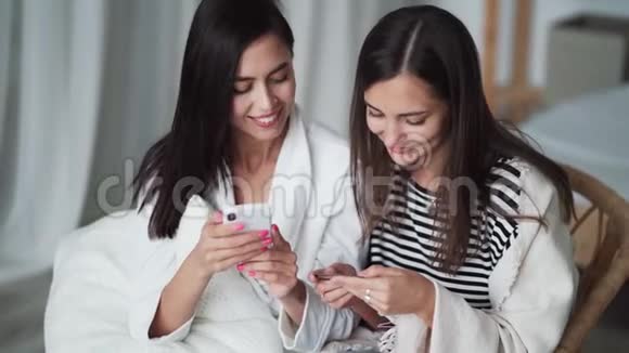 关闭两个女孩在网上购物从银行卡输入数据进入电话视频的预览图