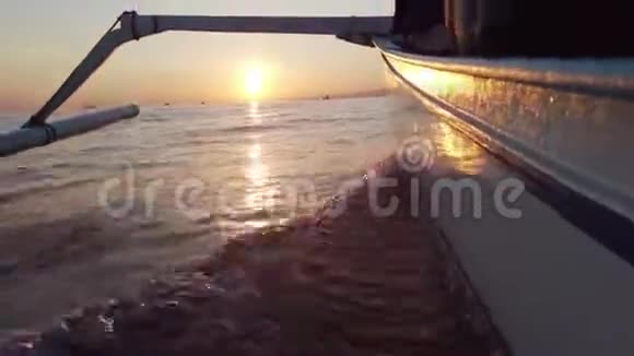 在开阔的海洋中带着波浪向日落移动的船视频的预览图
