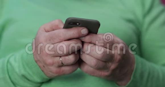 握着和使用现代智能手机的老人的手欧洲人5060岁老年人的概念视频的预览图