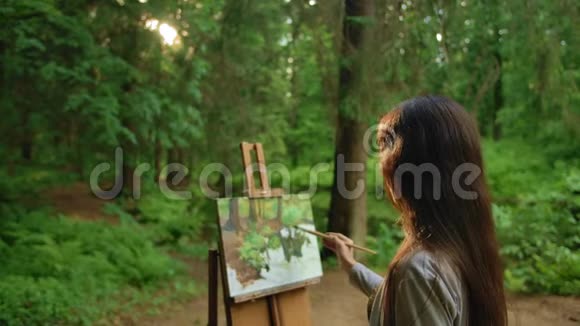 黑发女在公园里画风景油画视频的预览图