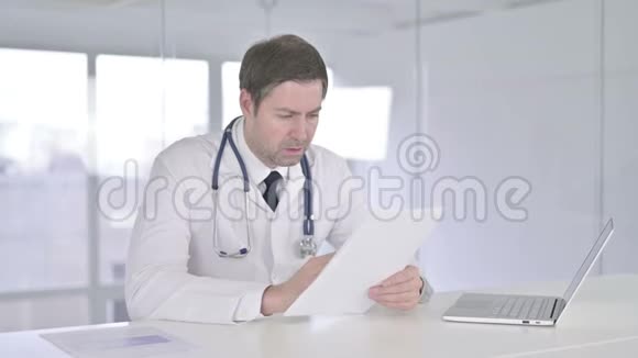 勤劳的中年医生在办公室阅读文件视频的预览图
