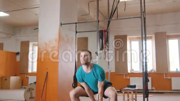 室内运动训练一个英俊的男子蹲在他的手中的重量视频的预览图