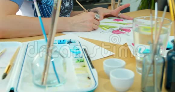 艺术家画花水彩画用刷子手绘有刷子的女性手手握刷子视频的预览图