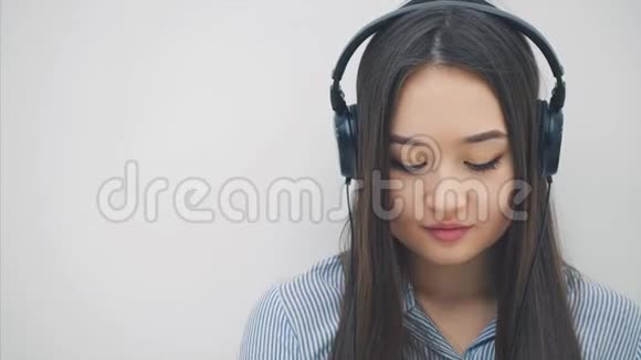 启发年轻的亚洲女孩坐在地板上耳机听音乐写作微笑和跳舞视频的预览图