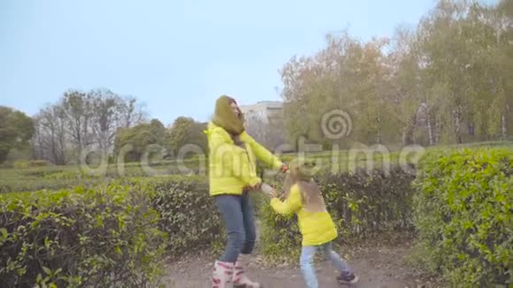 快乐的白人家庭穿着黄色外套在户外玩耍女儿在秋天的公园里缠着妈妈视频的预览图