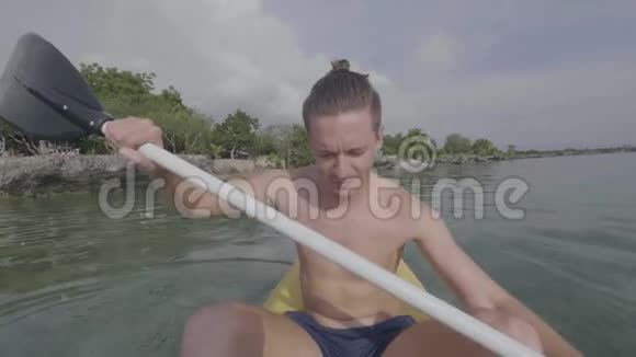 英俊的年轻人喜欢在热带度假胜地附近的海上皮划艇视频的预览图