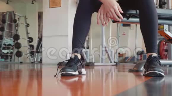 在健身馆里青年女子将训练鞋鞋带绳系紧健康和人的生活方式观念放松视频的预览图