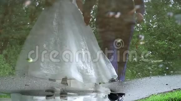 雨后一对新婚夫妇在人行道上的水坑里视频的预览图