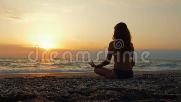一位年轻女性在日落时在海边或海边练习瑜伽视频的预览图