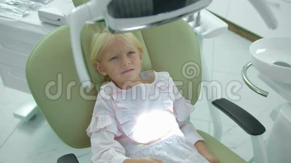 漂亮女孩坐在牙医椅上关掉一盏灯视频的预览图
