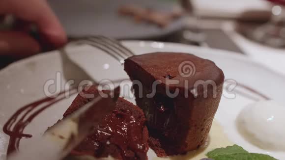 把巧克力松饼放在白色盘子里男人用叉子和刀切它嘴甜的景色不错视频的预览图