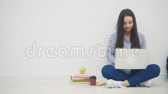 年轻的亚洲女学生坐在洛托斯的位置上用手提电脑用手指举起来就好像在拿着一个视频的预览图
