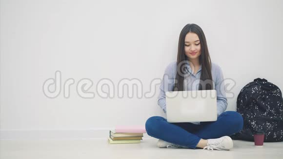 年轻的亚洲女士坐在地板上坐在洛托斯的位置上在她的笔记本电脑里搜索着什么东西从她的电脑里拿出苹果视频的预览图