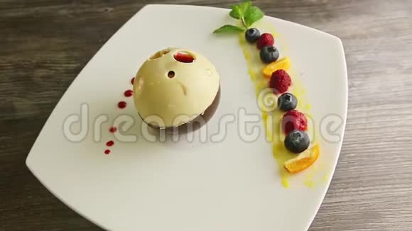 精美装饰的巧克力球形甜点在白色盘子上旋转视频的预览图