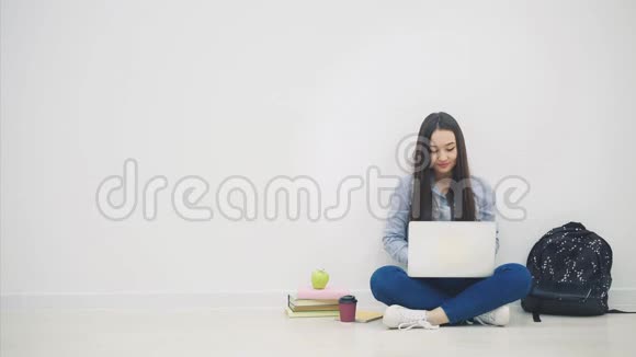一位亚洲女士坐在地板上拿着笔记本电脑举起双手挥舞着双手开心地笑着视频的预览图