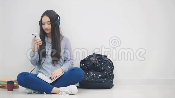 启发年轻的亚洲女孩坐在地板上做作业听音乐切换歌曲跳舞视频的预览图