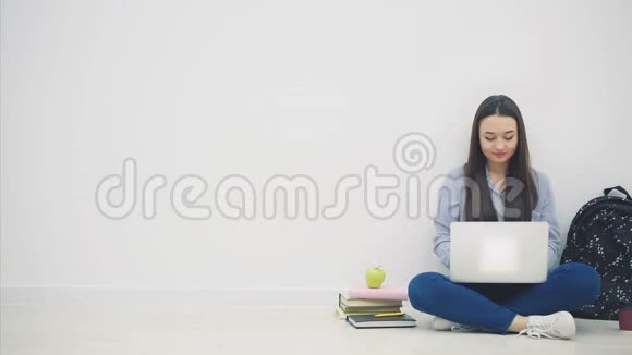 可爱的年轻亚洲女士坐在地板上以洛托斯的姿势在互联网上搜索点头学校视频的预览图