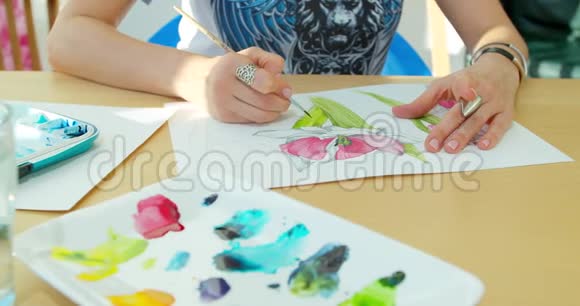 艺术家画花水彩画用刷子手绘有刷子的女性手手握刷子视频的预览图