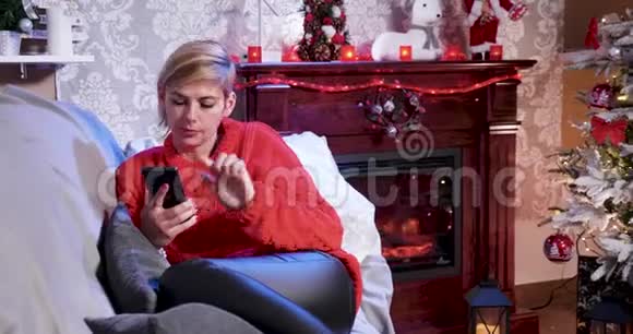 穿着红色毛衣的白人女性在手机上滚动视频的预览图