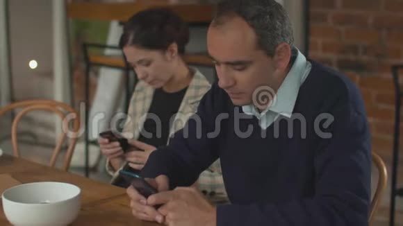 一对夫妇并排坐在一起双手拿着电话交谈视频的预览图