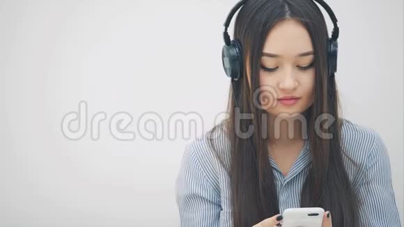 受启发的年轻亚洲女孩戴着耳机听着音乐跳舞对着镜头微笑视频的预览图