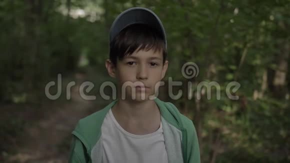 森林里一个滑稽男孩近距离看镜头的画像视频的预览图