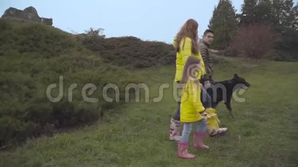 秋天美丽的高加索母亲小女儿和十几岁的儿子与大黑人杜伯曼漫步的侧面景色视频的预览图
