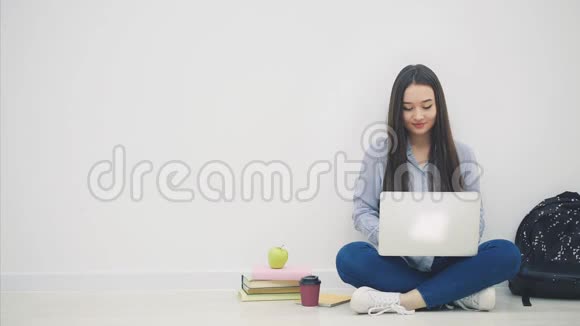 亚洲女士坐在地板上以洛托斯的姿势拿着笔记本电脑举起她的手快乐地微笑着作为胜利者视频的预览图