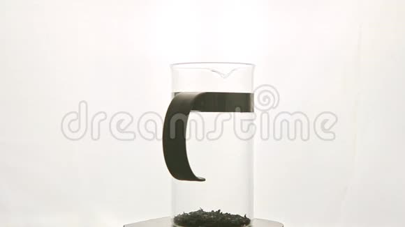 一个高高的玻璃茶壶茶叶在基座上与白色旋转视频的预览图