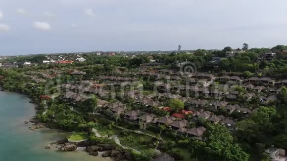 一架无人机飞过海滨的一个热带小屋村庄视频的预览图