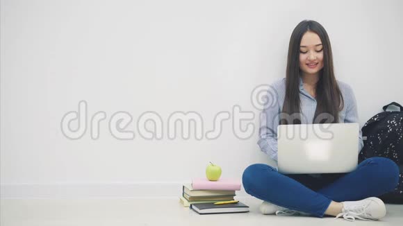 可爱的亚洲年轻女士坐在地板上坐在洛托斯的位置上手提电脑手指指着相机然后视频的预览图