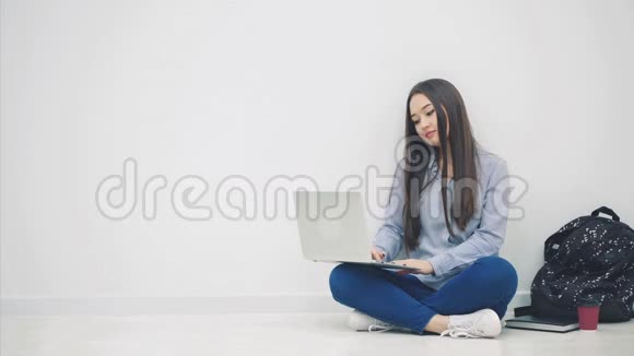 可爱的亚洲小姐坐在地板上坐在洛托斯的位置上手提电脑看着旁边伸出大拇指视频的预览图